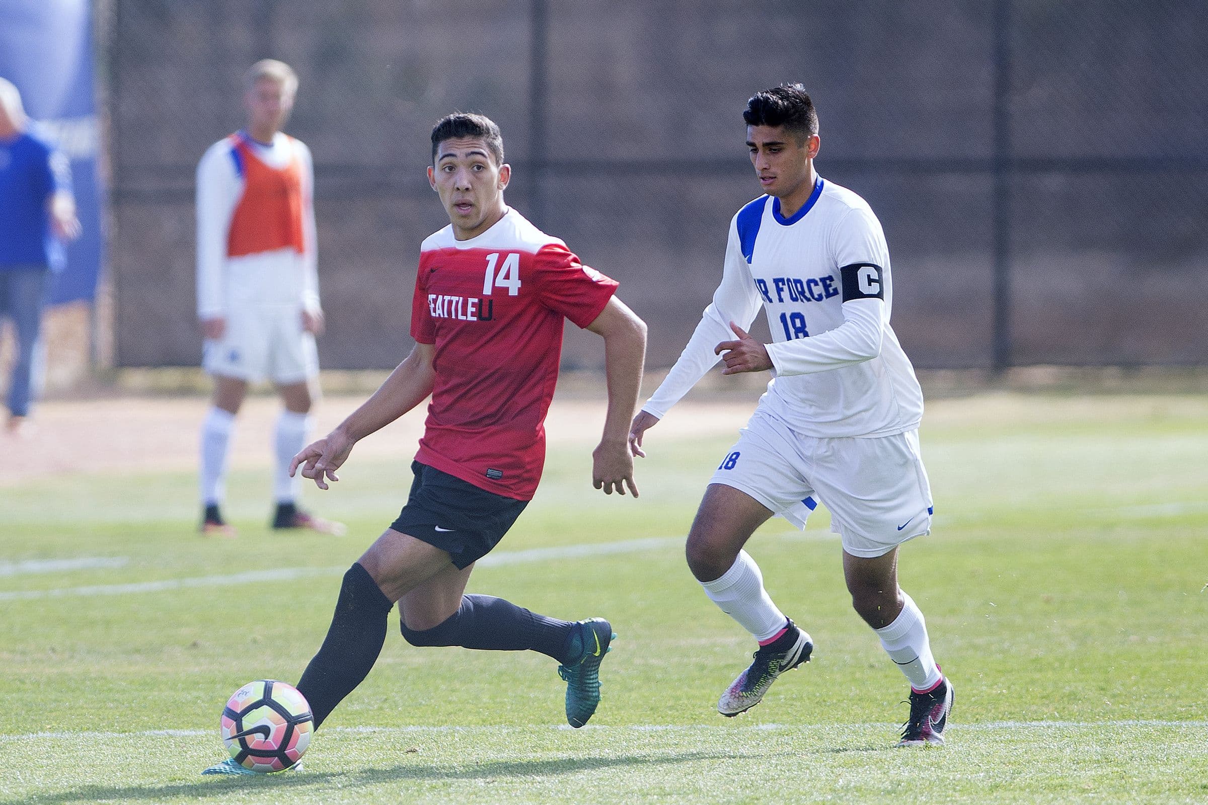 A Seattle U and an Air Force men's player dribbling side by side
